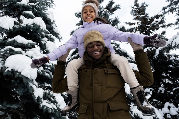 Foto gratuita ragazza che si diverte con suo padre in una giornata invernale nevosa