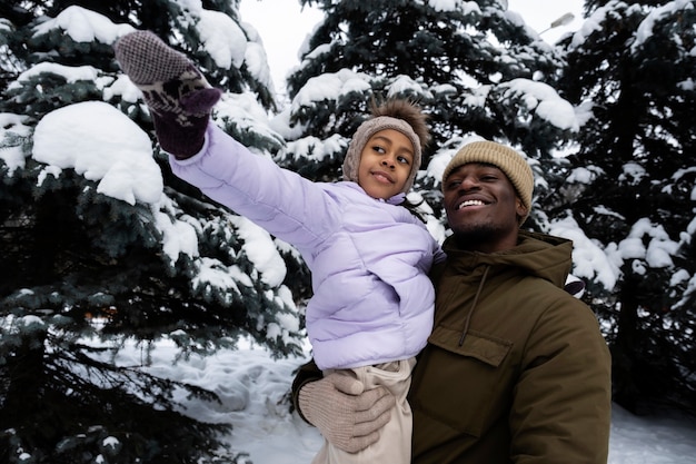 Foto gratuita ragazza che si diverte con suo padre in una giornata invernale nevosa