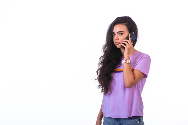 Молодая девушка разговаривает по телефону и разговаривает с черным смартфоном.
