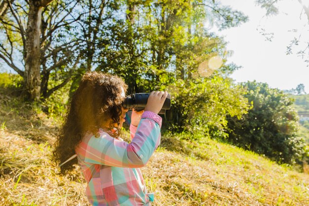 Young girl on hill with binoculars