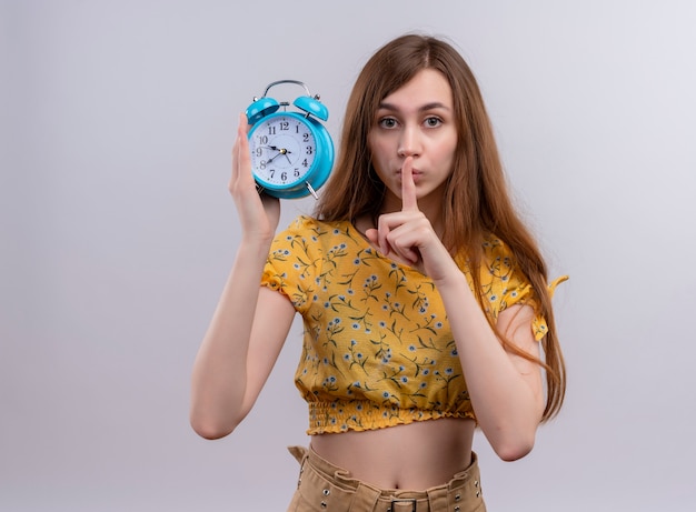 Young girl holding alarm clock on isolated white wall