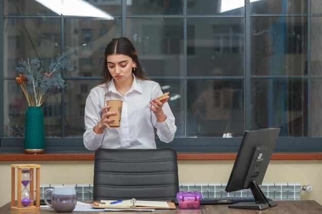 Young girl holding coffee cup and looking in it