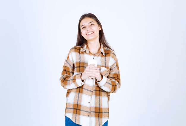 young girl holding cup of tea on white wall. 