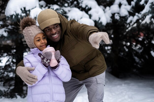 Young girl holding cup of warm drink while out on a winter day with her father