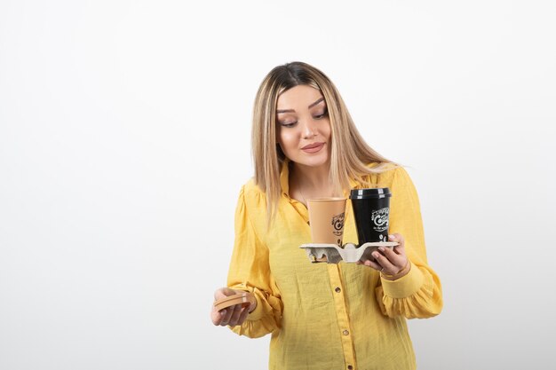 young girl holding cups of coffee and looking at lid.