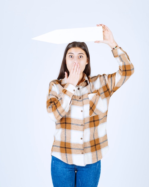 Young girl holding empty speech arrow pointer and covering her mouth. 