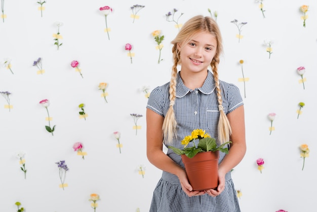 Free photo young girl holding flowers pot