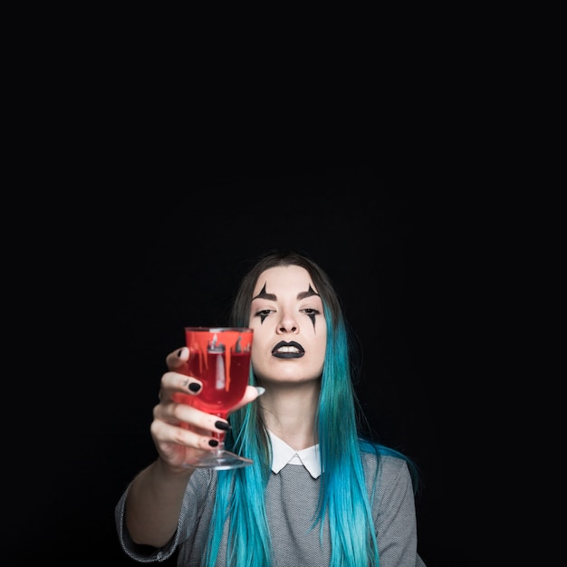 Young girl holding glass goblet with red liquid