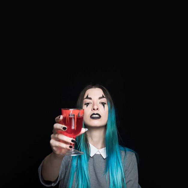 Young girl holding glass goblet with red liquid