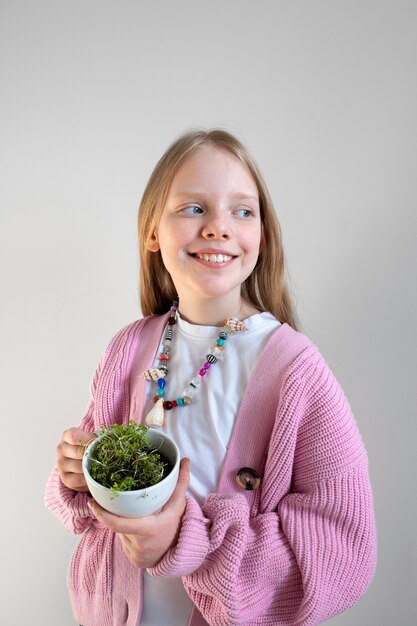 Young girl holding greenery planted in upcycled pot