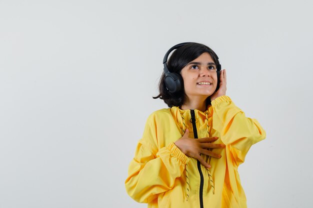 어린 소녀 손으로 헤드폰을 들고 노란색 폭격기 재킷에서 음악을 듣고 행복을 찾고
