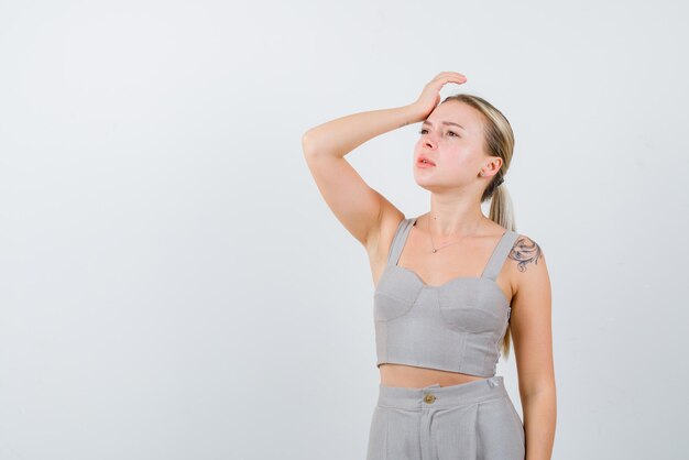 Young girl holding her hands on her forehead on white background