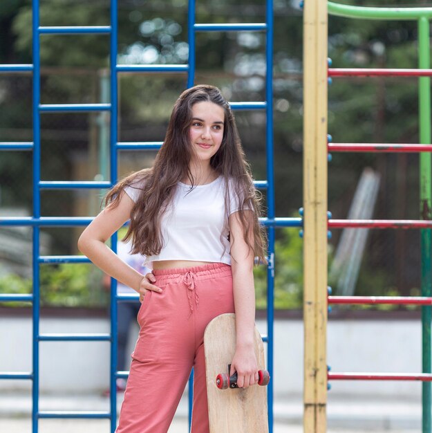 Young girl holding her skateboard outside