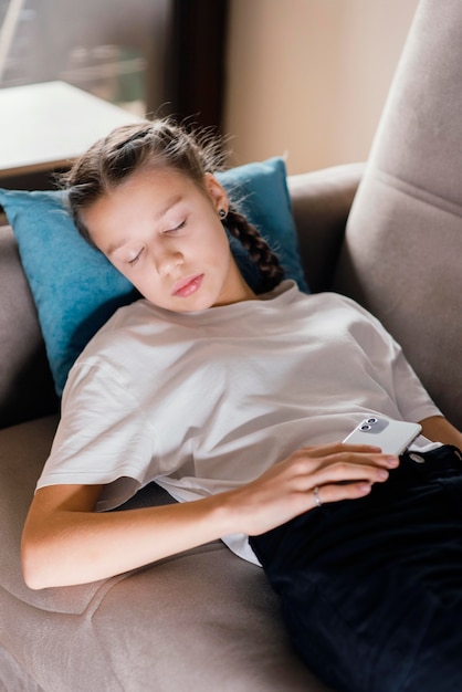 Young girl holding mobile while asleep