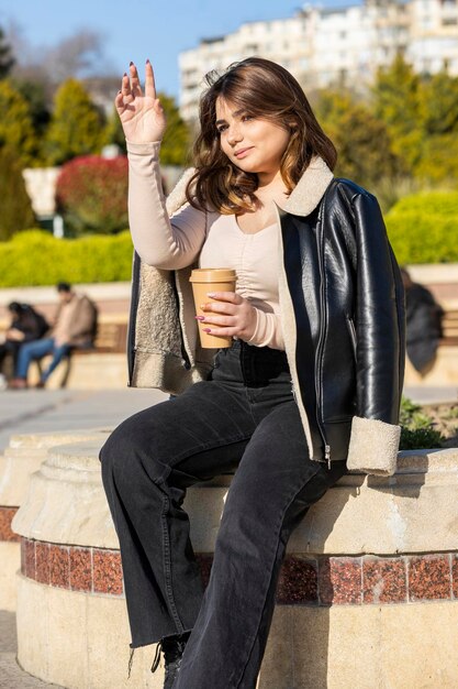 Young girl holding mug and raised her hand while looking away High quality photo