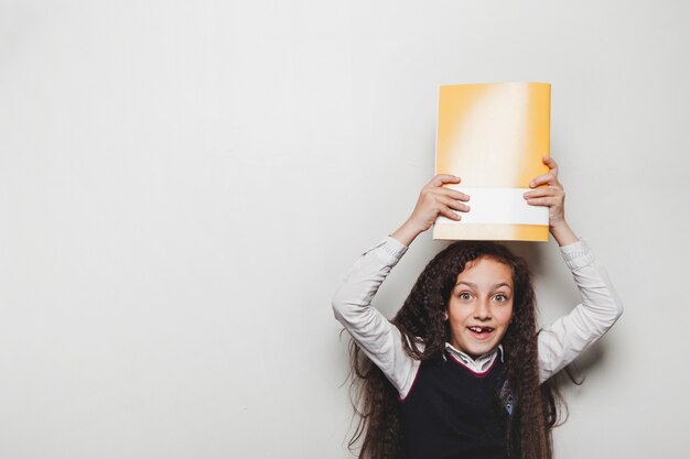 Young girl holding notebook over head