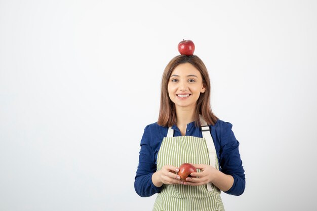 young girl holding red apples while smiling on white.