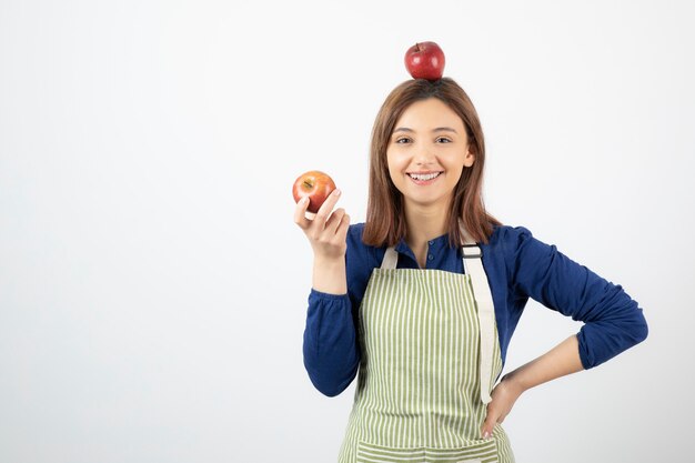 young girl holding red apples while smiling on white.