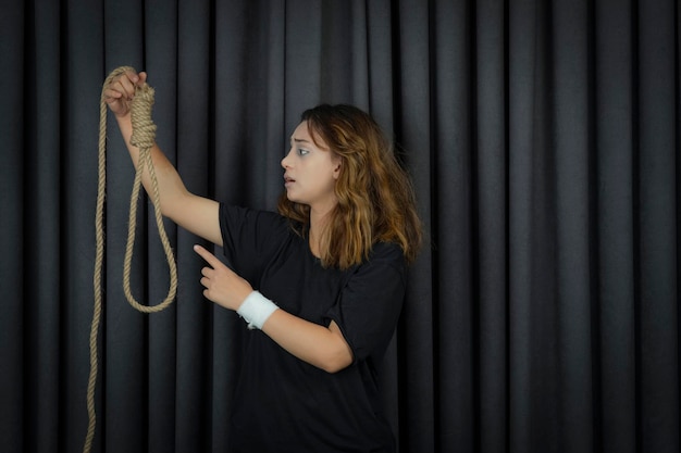 Молодая девушка держит веревку для самоубийства и говорит ей нет. Фото высокого качества