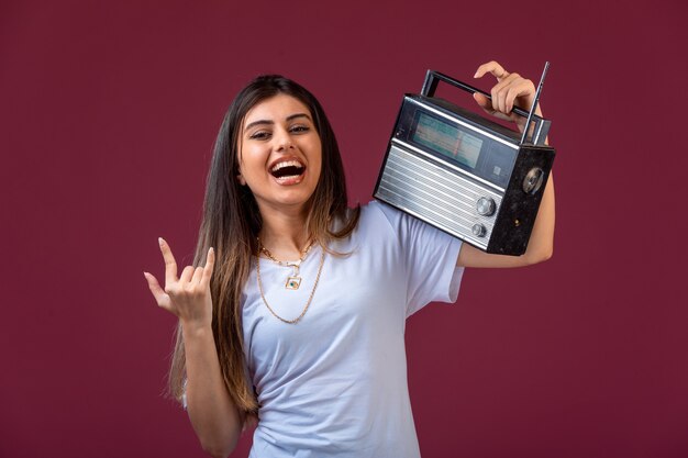 Young girl holding a vintage radio on her shoulder and having fun