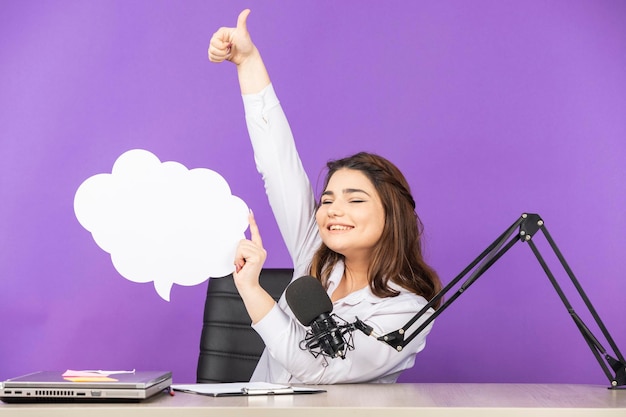 Free photo young girl holding white paper speech bubble in cloud shape and raised thumb up high quality photo