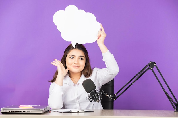 Young girl holding white paper speech bubble in cloud shape and smiling to the camera High quality photo