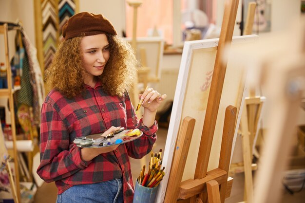 Young girl holds a palette with oil paints  and a brush