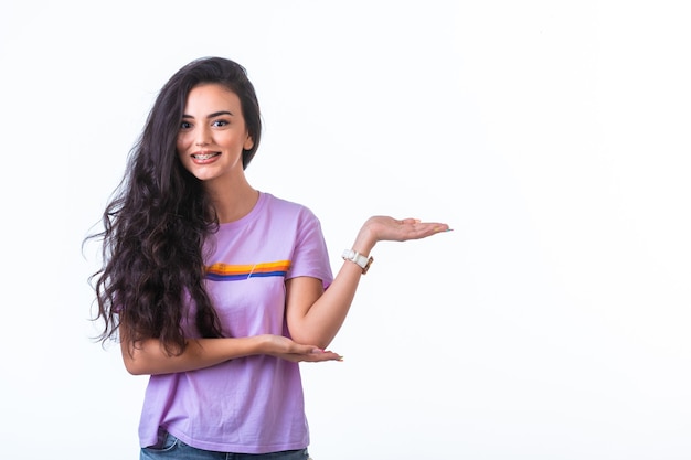 Young girl introducing something with hand gests on white surface