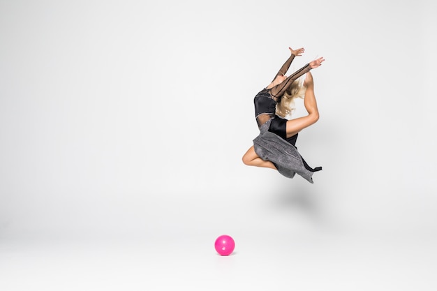Молодая девушка занимается художественной гимнастикой с мячом