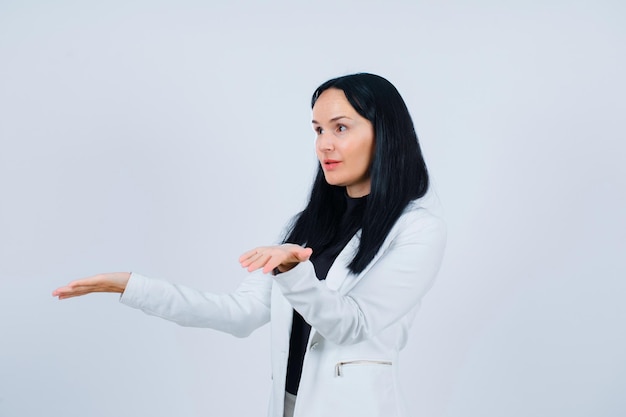 Young girl is looking away by opening wide her arms on white background