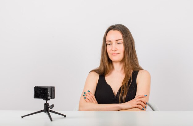 Young girl is looking at camera by crossing arms on white background