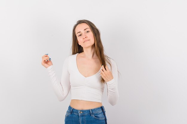 Young girl is looking at camera by holding hair on white background