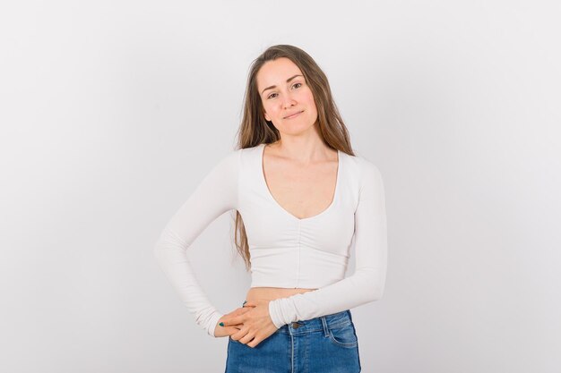 Young girl is looking at camera by holding hands together on waist on white background