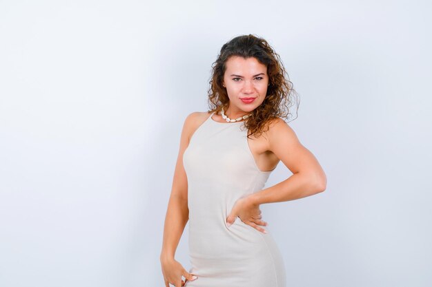 Young girl is looking at camera by putting hand on waist on white background