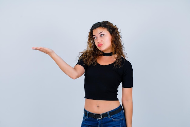 Young girl is looking left and pointing left with hand on white background