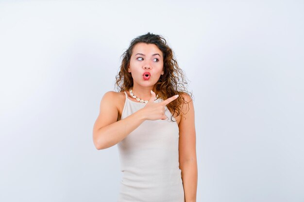 Young girl is looking right and pointing right with forefinger on white background