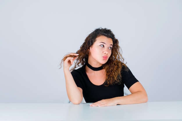 Young girl is looking up by holding hair on white background