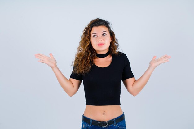 Young girl is looking up by opening wide her hands on white background