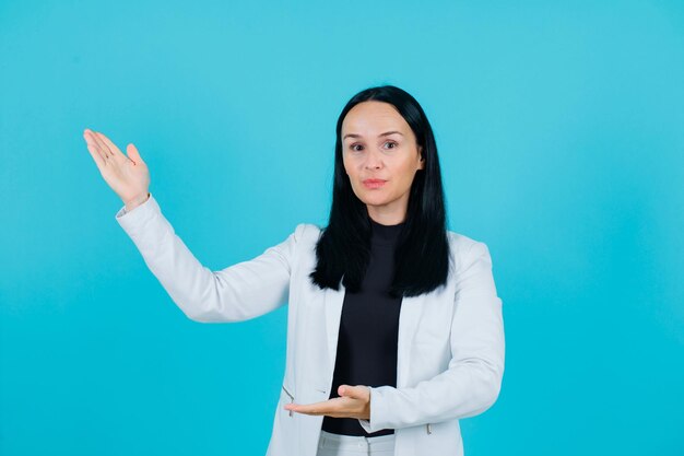 Young girl is pointing left up with hand on blue background