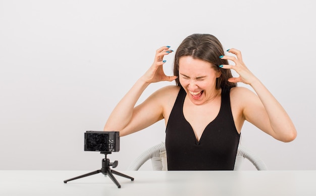 Young girl is posing at camera by screaming and showing claws gestures on white background