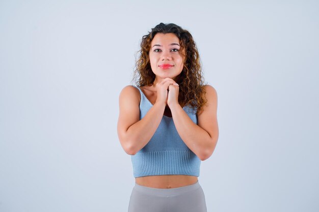 Young girl is praying by holding hands together on chest on white background