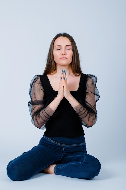 Free photo young girl is praying by holding hands together on white background