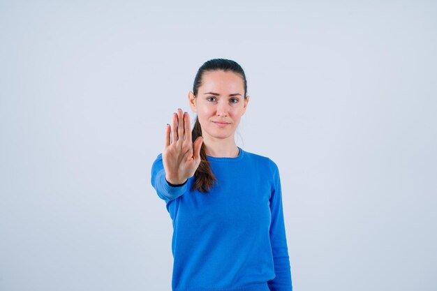 Young girl is showing stop gesture on white background