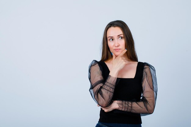 Young girl is thinking by putting hand on chin on white background