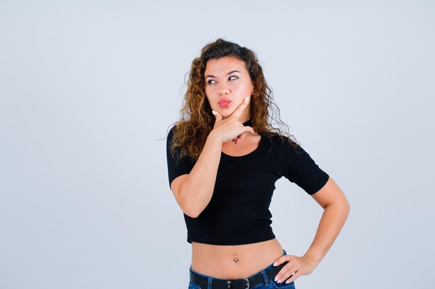 Young girl is thinking by putting hand on chin on white background