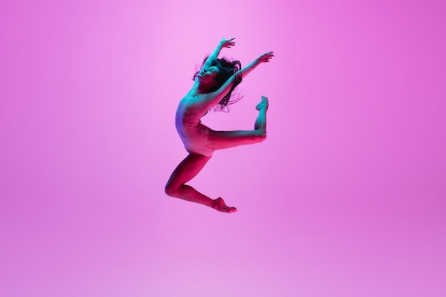 Young girl jumping on pink wall