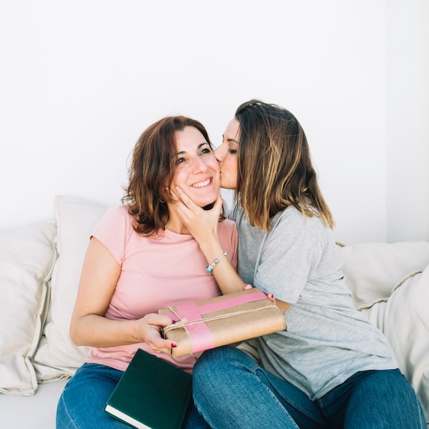 Young girl kissing woman in cheek at home