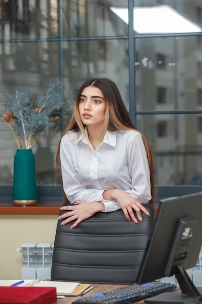 La ragazza si appoggia sulla sedia e distoglie lo sguardo foto di alta qualità