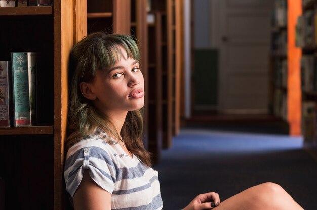 Young girl leaning against a bookshelf