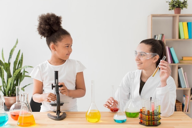 Young girl learning chemistry from female scientist